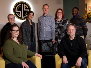 group of people smiling, two sitting down, five standing