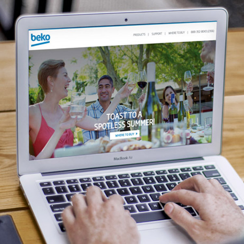 person types on a computer, display is of the Beko website