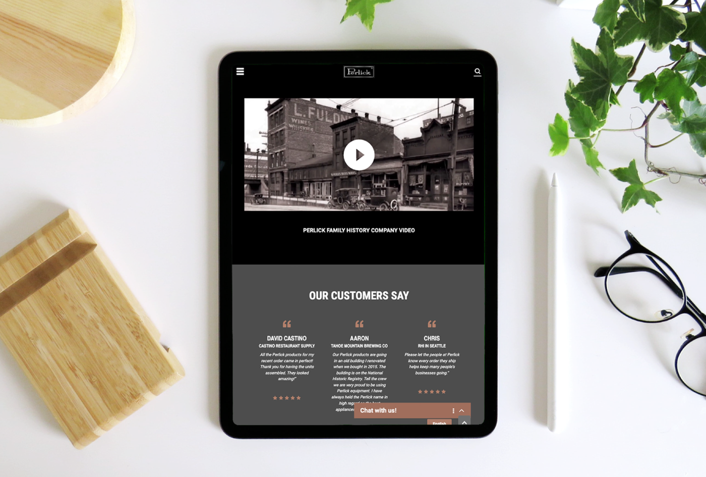 tablet sitting on desk next to apple pencil, plant, glasses and wooden objects, screen shows Perlick website