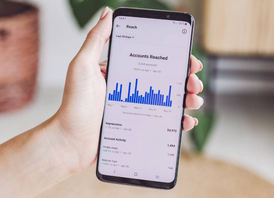 analytics-web-dev a person holds a phone, on the phone is a bar graph labelled Accounts Reached