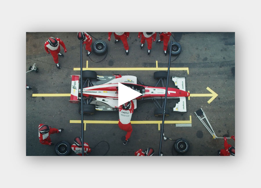 Video of a pit crew attending a racecar with a play button on top of the image