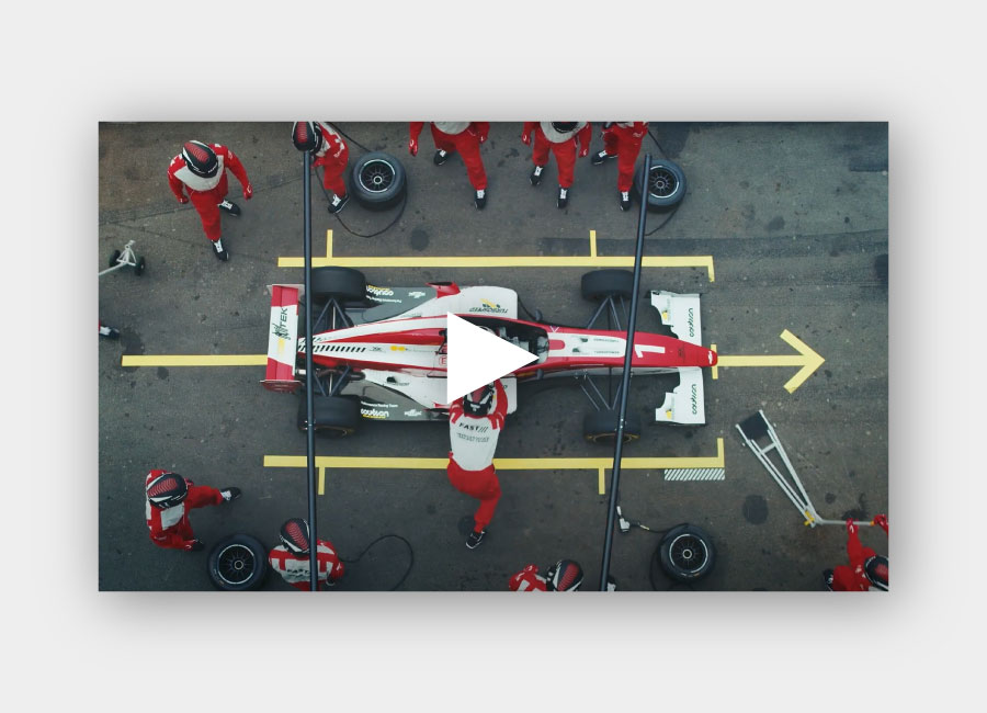 canon-video-web-dev-page Video of a pit crew attending a racecar with a play button on top of the image