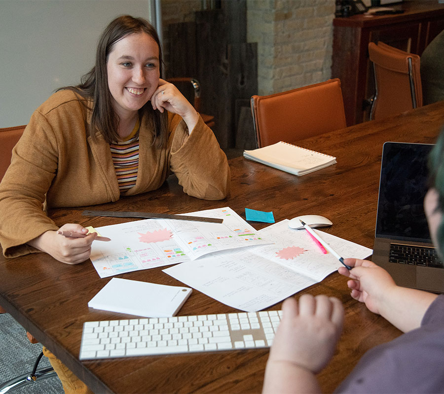 staff-alison-1122-01 woman smiling at conference table with documents laid out