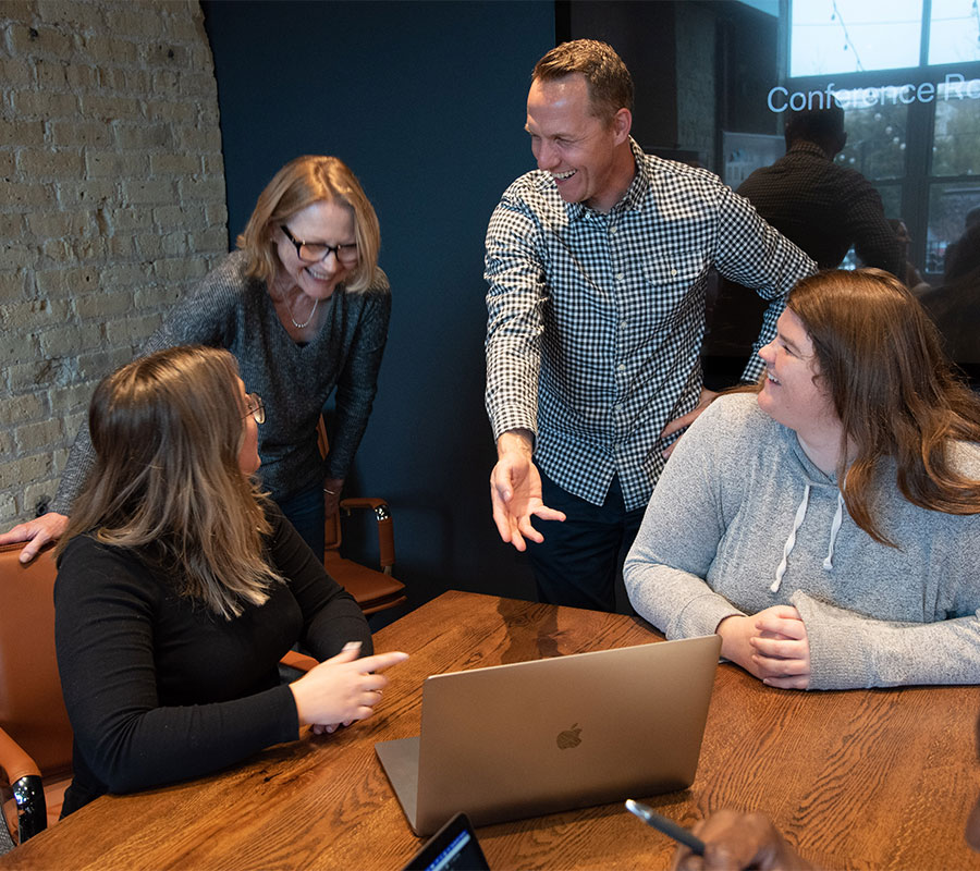 staff-chris-1122-01 coworkers laughing and discussing in front of a laptop