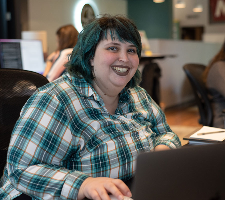 staff-jenna-1122-01 woman with short hair smiling at desk