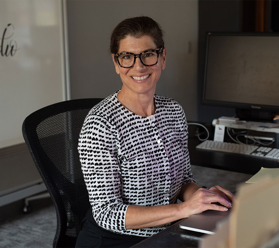 woman with glasses smiling at desk