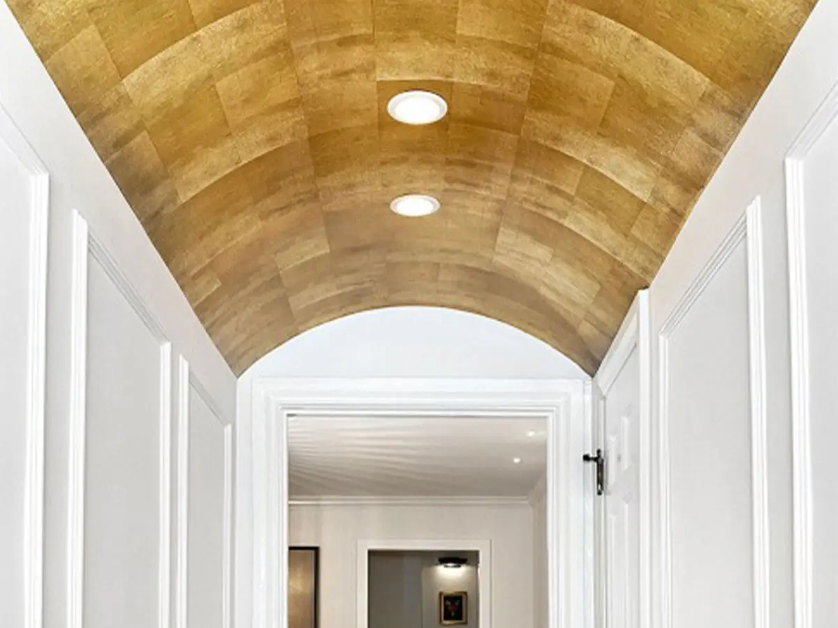 White paneled hallway with archway with award winning gold wallpaper on the arch